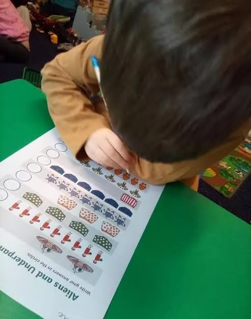 A child working on a counting activity at the table