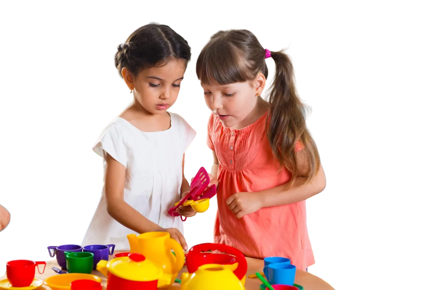 Two young girls playing together with a colourful toy tea set